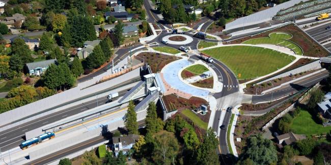 Aerial photo of a landscaped freeway lid over SR 520 at 92nd Avenue Northeast in Clyde Hill, with a transit bus leaving a median bus station located beneath the lid. 